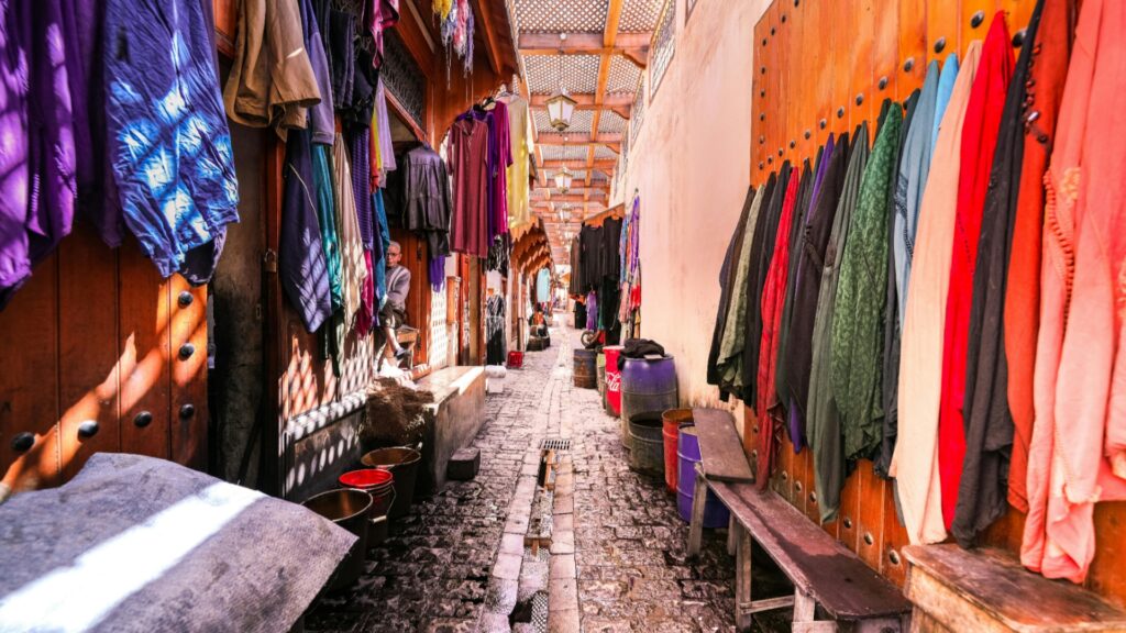 Grupo de viajeros explorando la medina de Fez con guía local, arquitectura islámica y puerta decorada, experiencia cultural en tours en Marruecos.