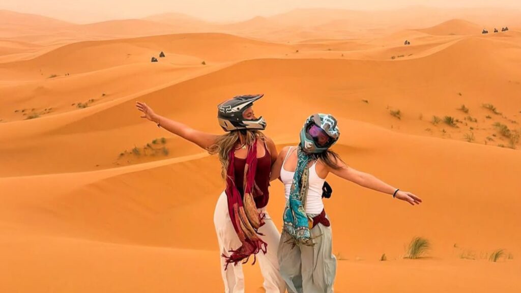Dunas infinitas del desierto del Sahara en Marruecos, cielo estrellado sobre campamento bereber, paisaje desértico con montañas al fondo.