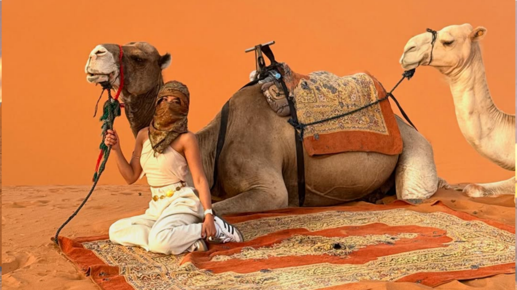 Caravana de camellos recorriendo las dunas doradas del desierto del Sáhara al atardecer. Reserva tu tour al desierto de Merzouga con Haya Viajes.