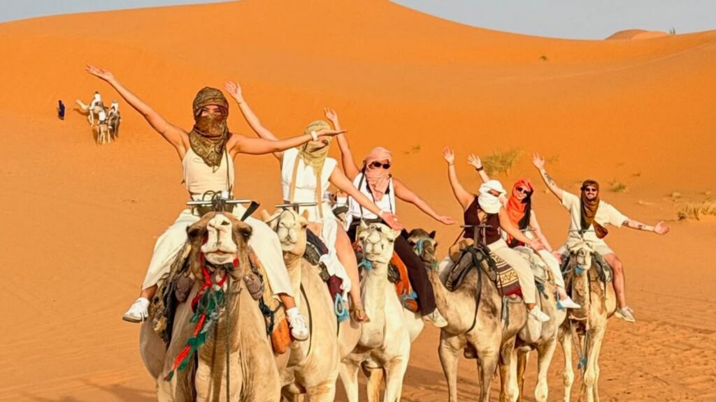 Caravana de camellos avanzando entre las dunas de Erg Chebbi en el desierto de Merzouga. Reserva tu tour al desierto de Merzouga con Haya Viajes.