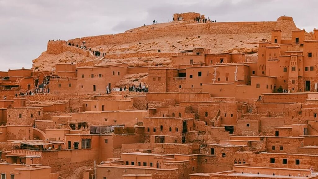 Vista panorámica de la kasbah de Ait Ben Haddou con el río y las montañas de fondo, fortaleza bereber de barro, Patrimonio de la Humanidad en ruta por Marruecos.