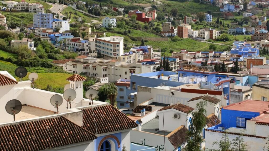 Callejón azul y blanco en Chefchaouen con macetas de flores, cascada de la plaza Uta el-Hammam, destino imprescindible en tours en Marruecos.